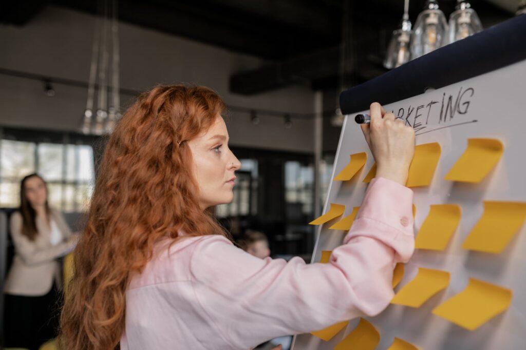 photo of a woman writing on a whiteboard with sticky notes 7 ps marketing